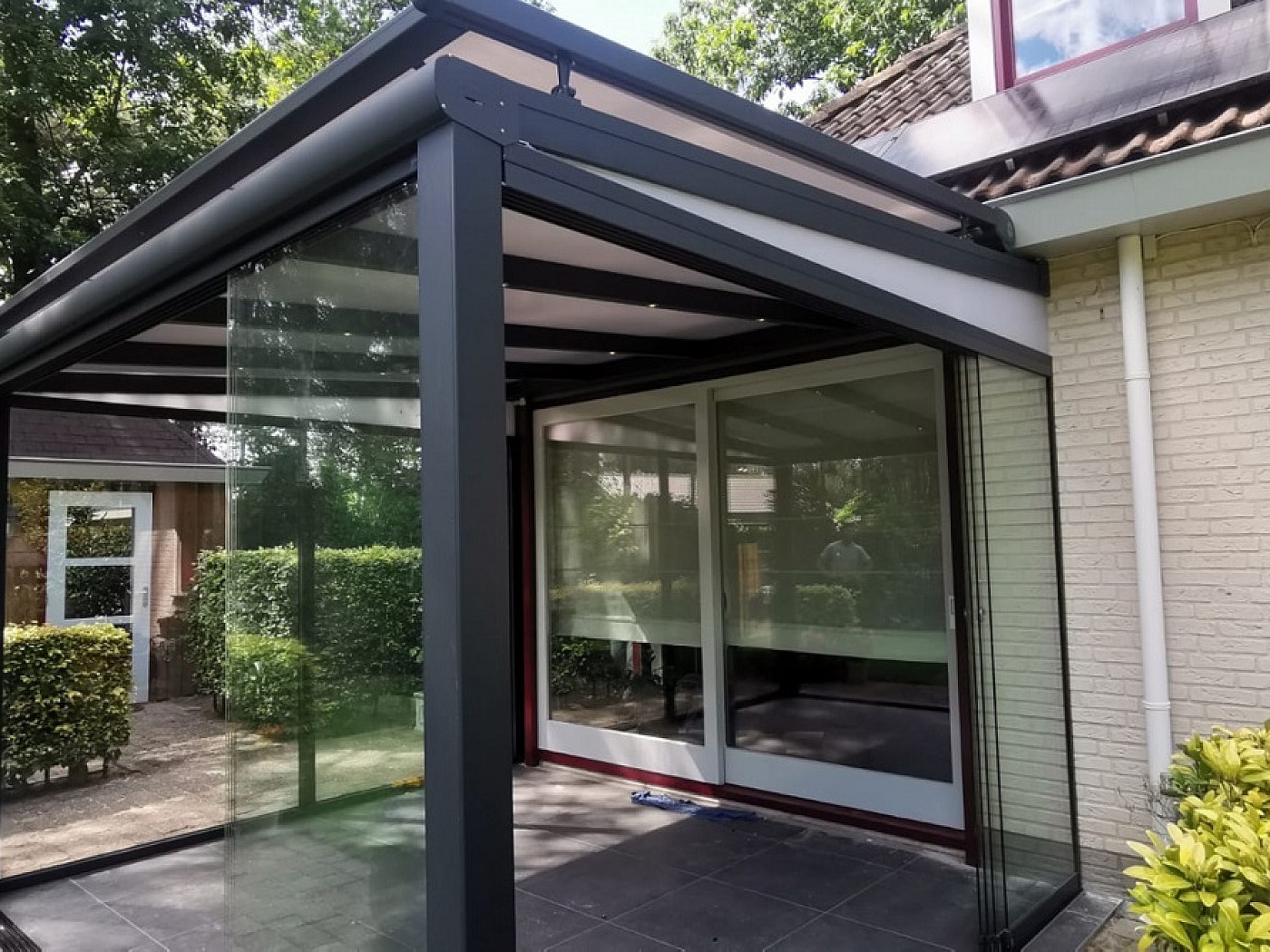 Overkapping op staanders zonwering met schuifdeuren aan muur